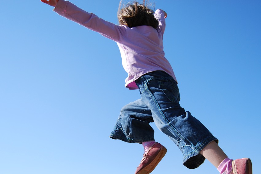 flying girl in pink shoes and lilac pullover against sky background