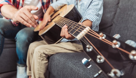 lärare visar elev hur man spelar gitarr