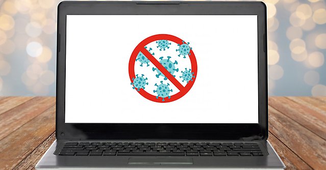 bild på en dator och på skärmen en illustration över coronaviruset med en stoppskylt över
